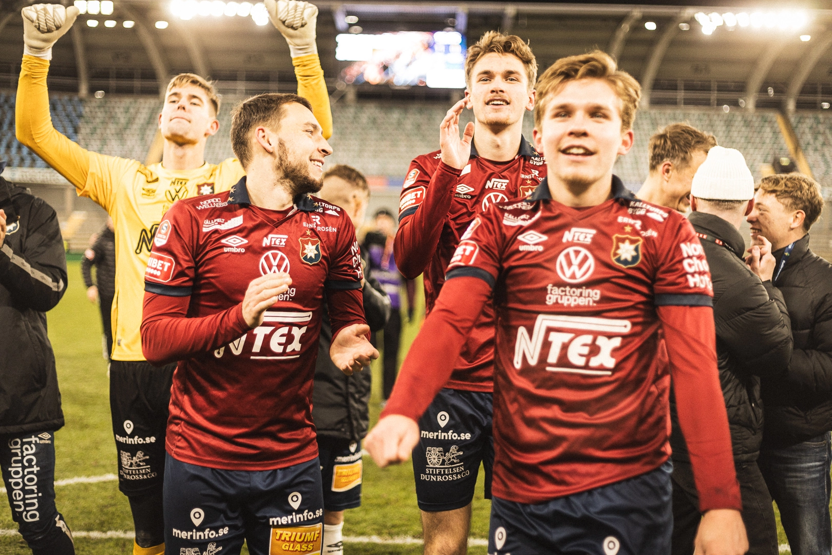 Örgryte IS-spelare i vinröda matchställ firar på planen efter en seger.