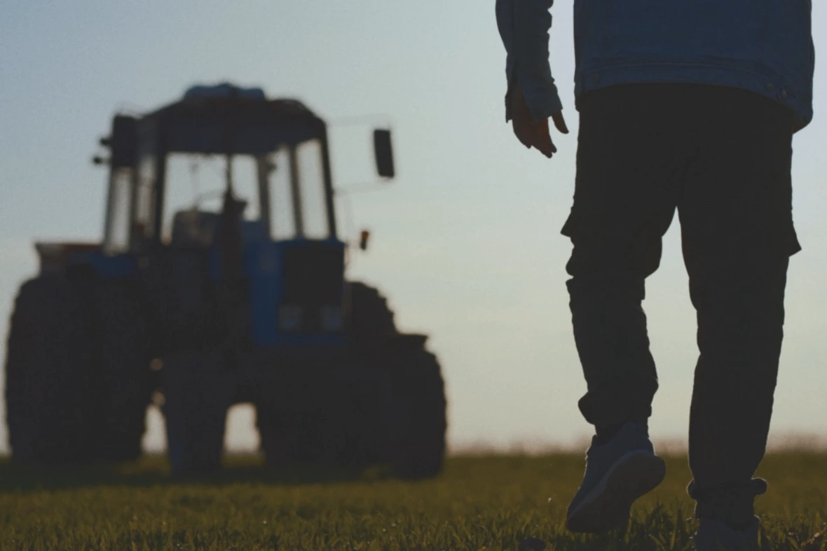 Lantbrukare går på ett fält mot en traktor i bakgrunden.